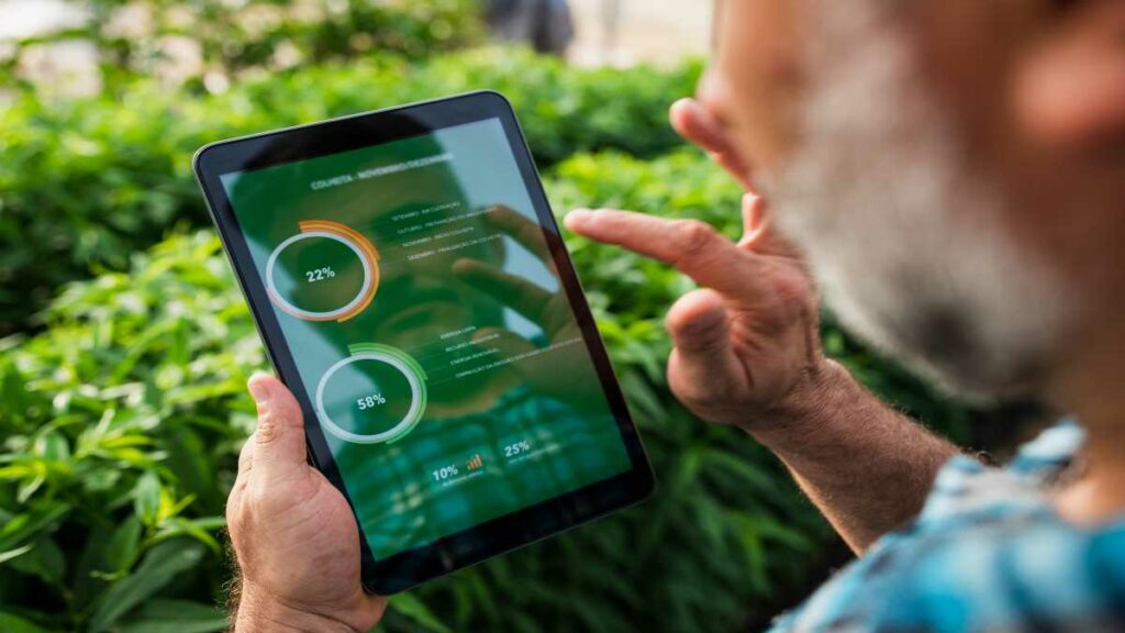 Homem segurando um tablet no meio da plantação