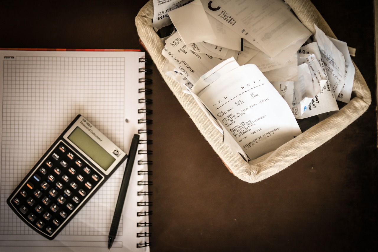 Calculadora sob um caderno e uma caixa de documentos fiscais ao lado